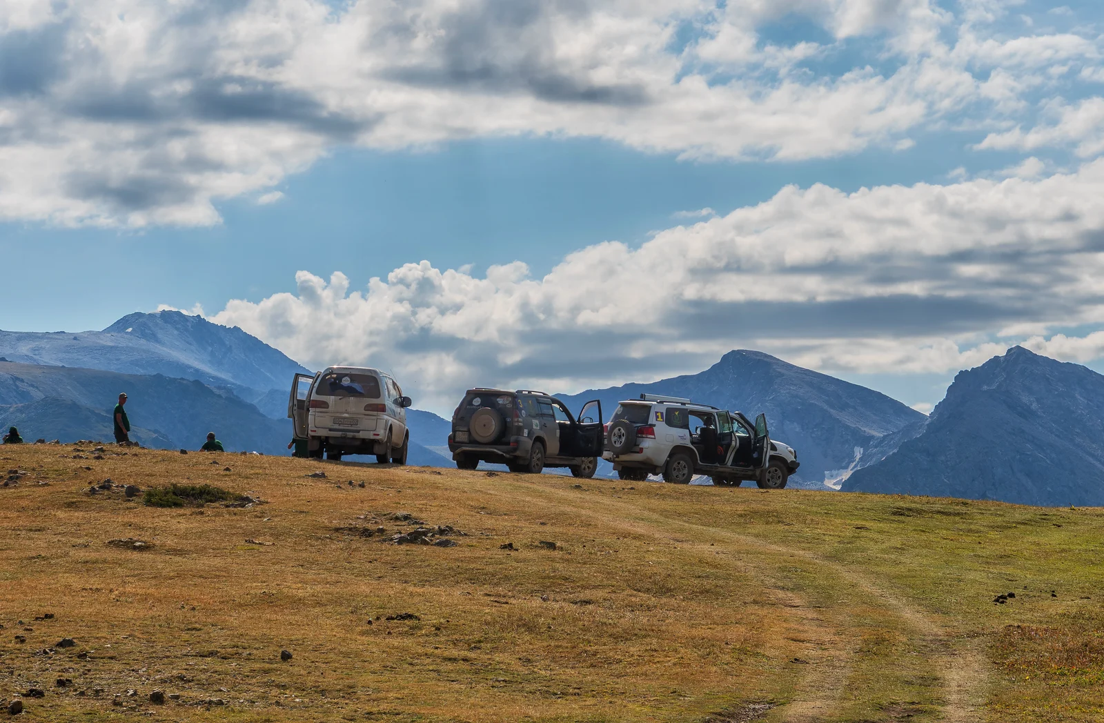 Off-road vehicles and travellers on a high mountain plateau