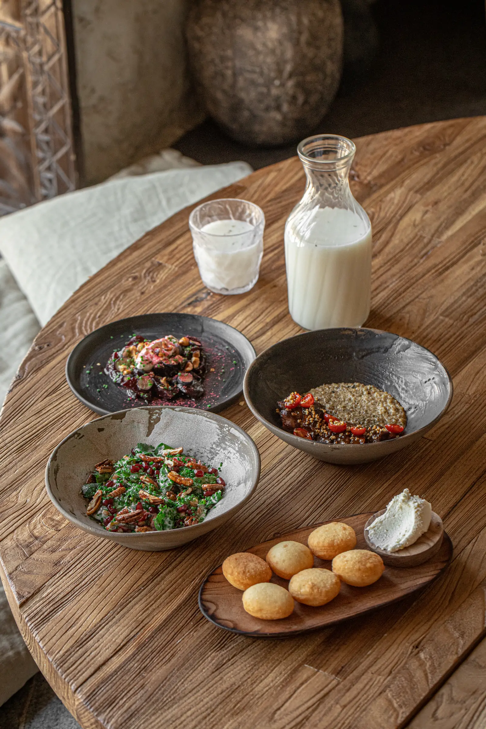 A round wooden table laid with Kazakh dishes, baursak and a carafe of milk