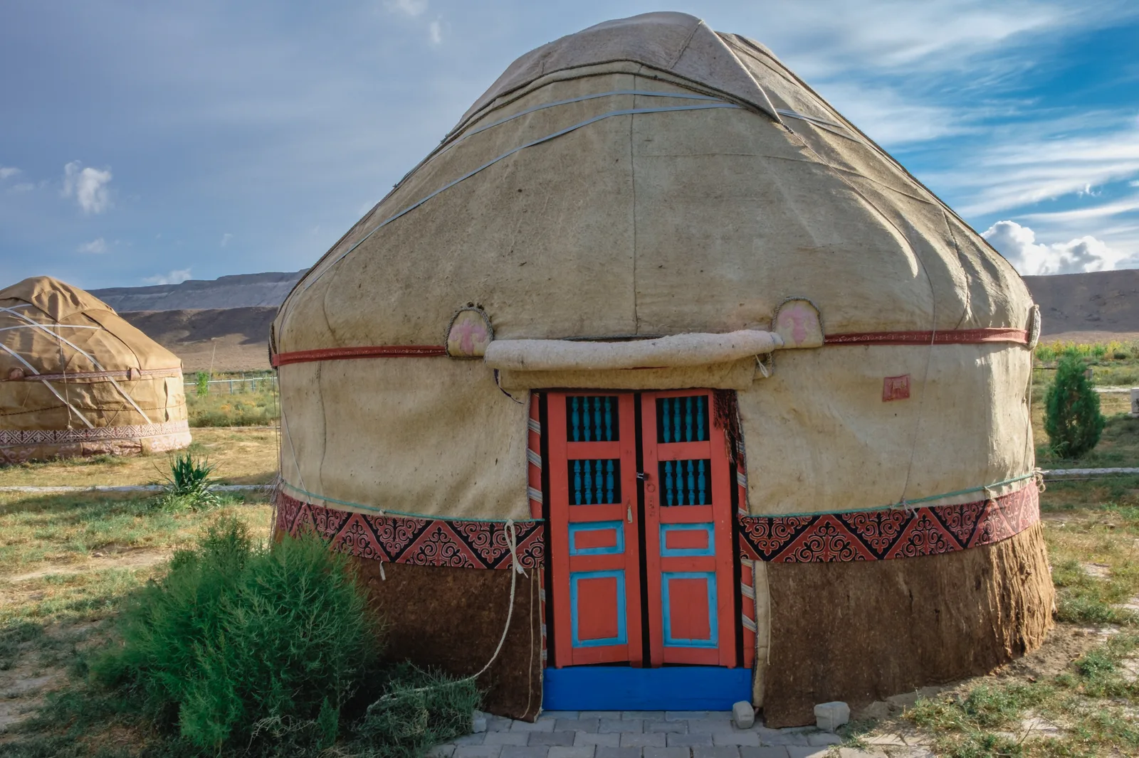 A felt yurt with a painted wooden door in the steppe