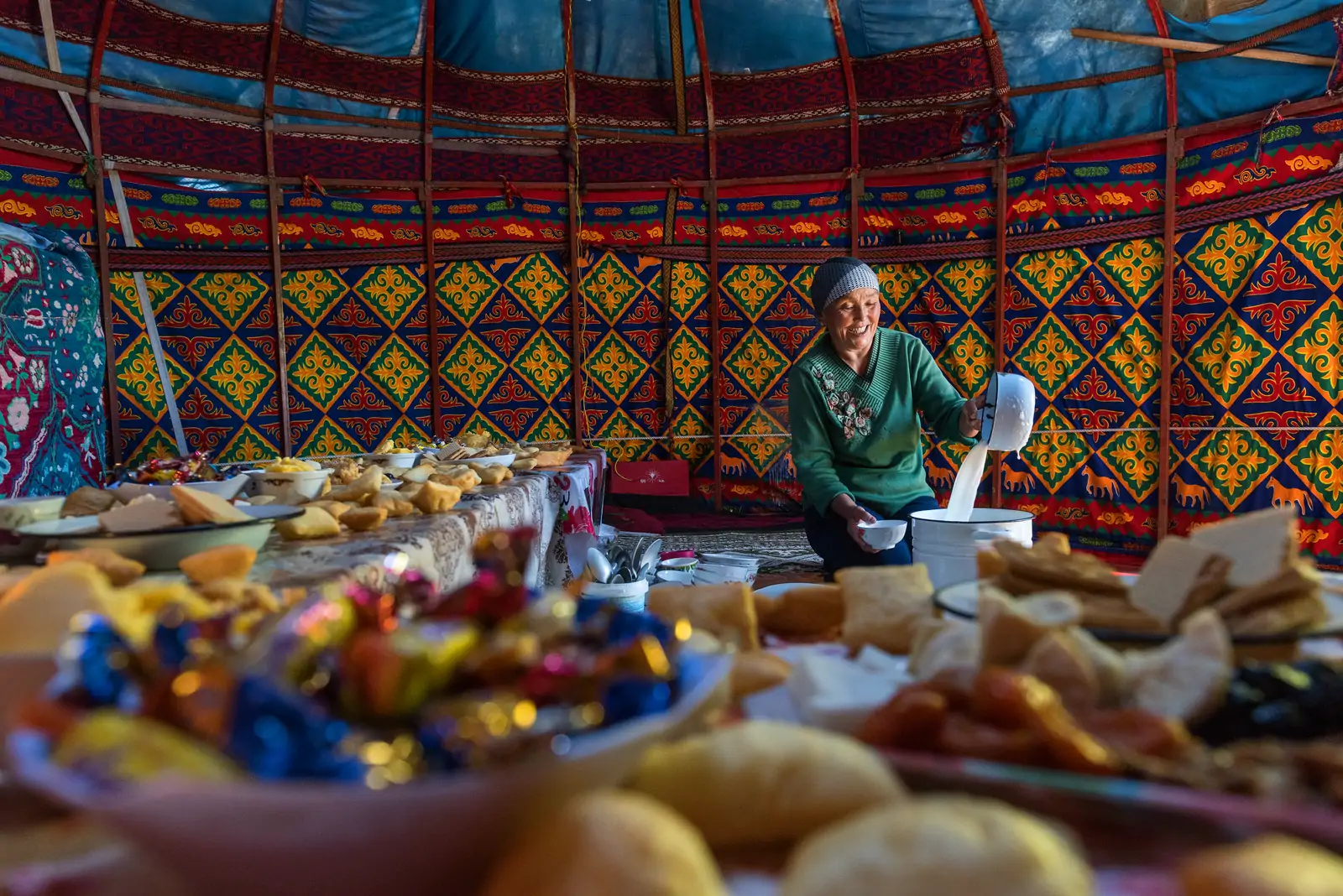 A host at a laid table inside a decorated yurt